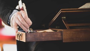 The hand of historic interpreter Bill Barker portrays Thomas Jefferson dipping a quill pen in ink to write at a small desk.